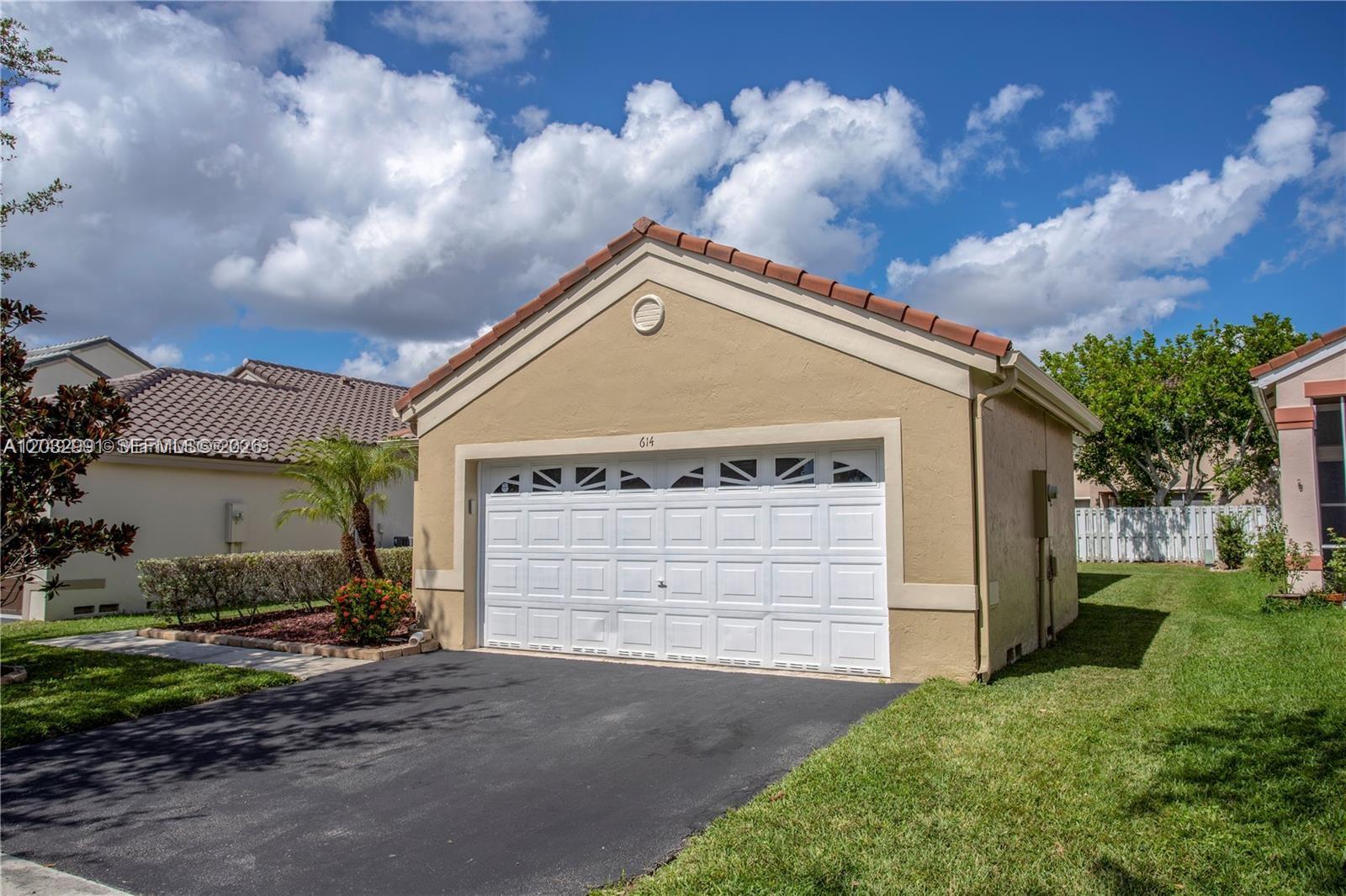 A tan, single-story detached garage with a white sectional door and a tiled roof — 614 Stanton Ln, Weston FL 33326, WESTON, FL