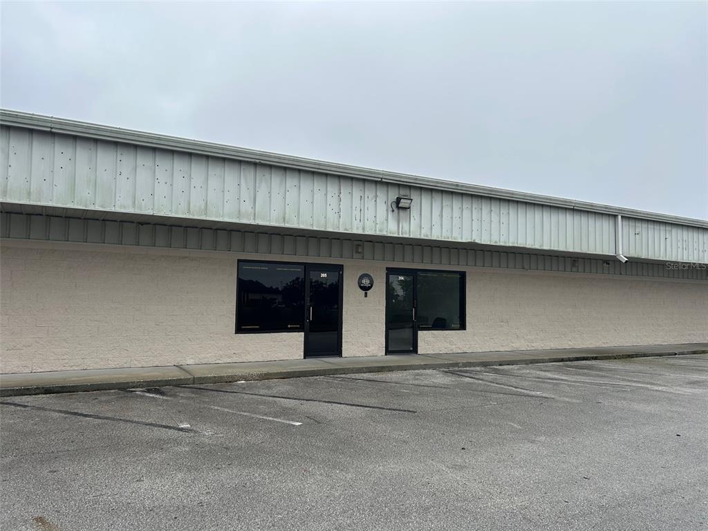 A single-story commercial building with two glass-paneled entrance doors and a paved parking lot — 11601 S ORANGE BLOSSOM TRAIL UNIT 204, ORLANDO, FL