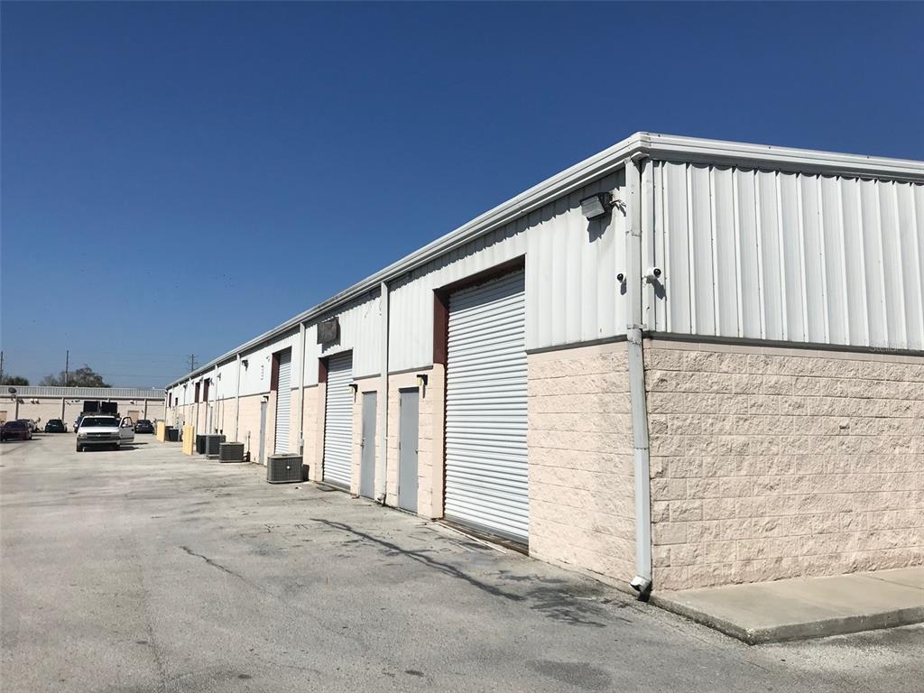 A large multi-tenant plaza sign stands beside a road under a blue sky — 11601 S ORANGE BLOSSOM TRAIL UNIT 204, ORLANDO, FL