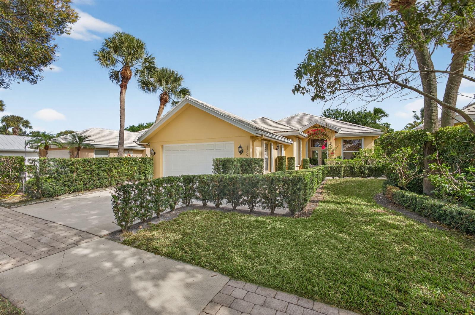 A yellow single-story house with a white garage and manicured hedges in the front yard — 1180 Gator Trail, West Palm Beach FL 33409, WEST PALM BEACH, FL