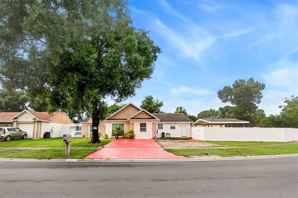 A single-story house features a bright red driveway, a large tree, and a white fence — 8903 CAMINO VILLA, TAMPA, FL