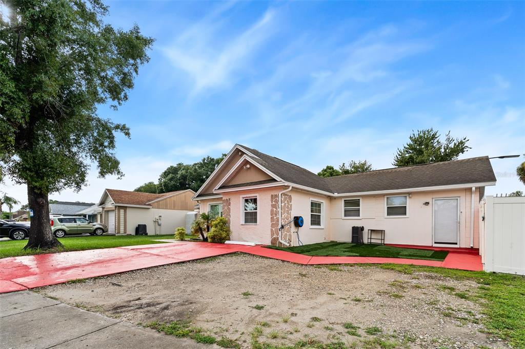 A single-story house with a painted red driveway and walkway, stone accents, and a lawn — 8903 CAMINO VILLA, TAMPA, FL