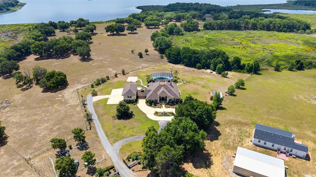 An aerial view shows a large house with a pool, outbuildings, and trees near water — 17269 B SE 260TH AVENUE ROAD, UMATILLA, FL