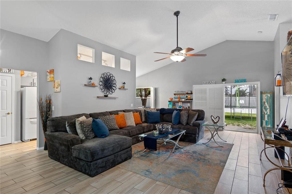 A living room features a large sectional sofa, a ceiling fan, and tile flooring — 541 HEATHER GLEN DR, WINTER HAVEN, FL