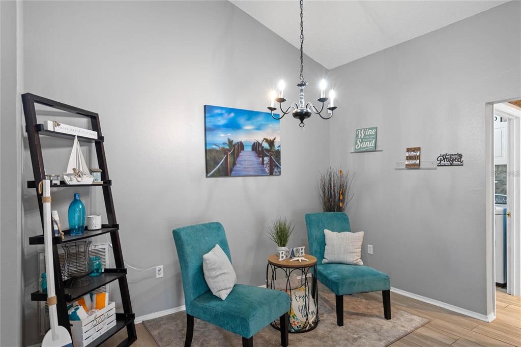 A dining area features two teal chairs, a small round table, and a black shelving unit — 541 HEATHER GLEN DR, WINTER HAVEN, FL