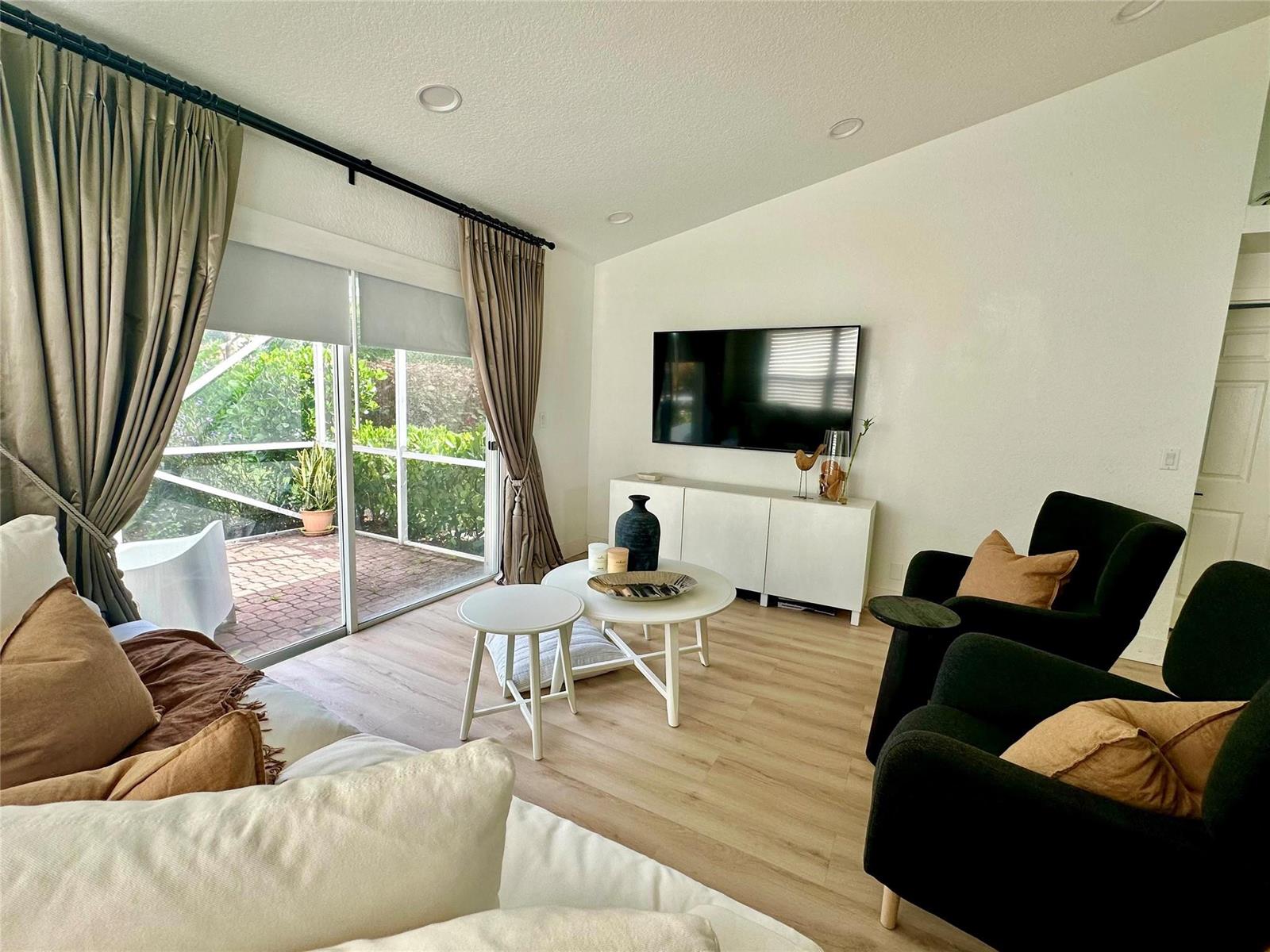 A living room features a wall-mounted television, white media console, two black armchairs, and curtains — 7267 Panache Way, Boca Raton FL 33433, BOCA RATON, FL