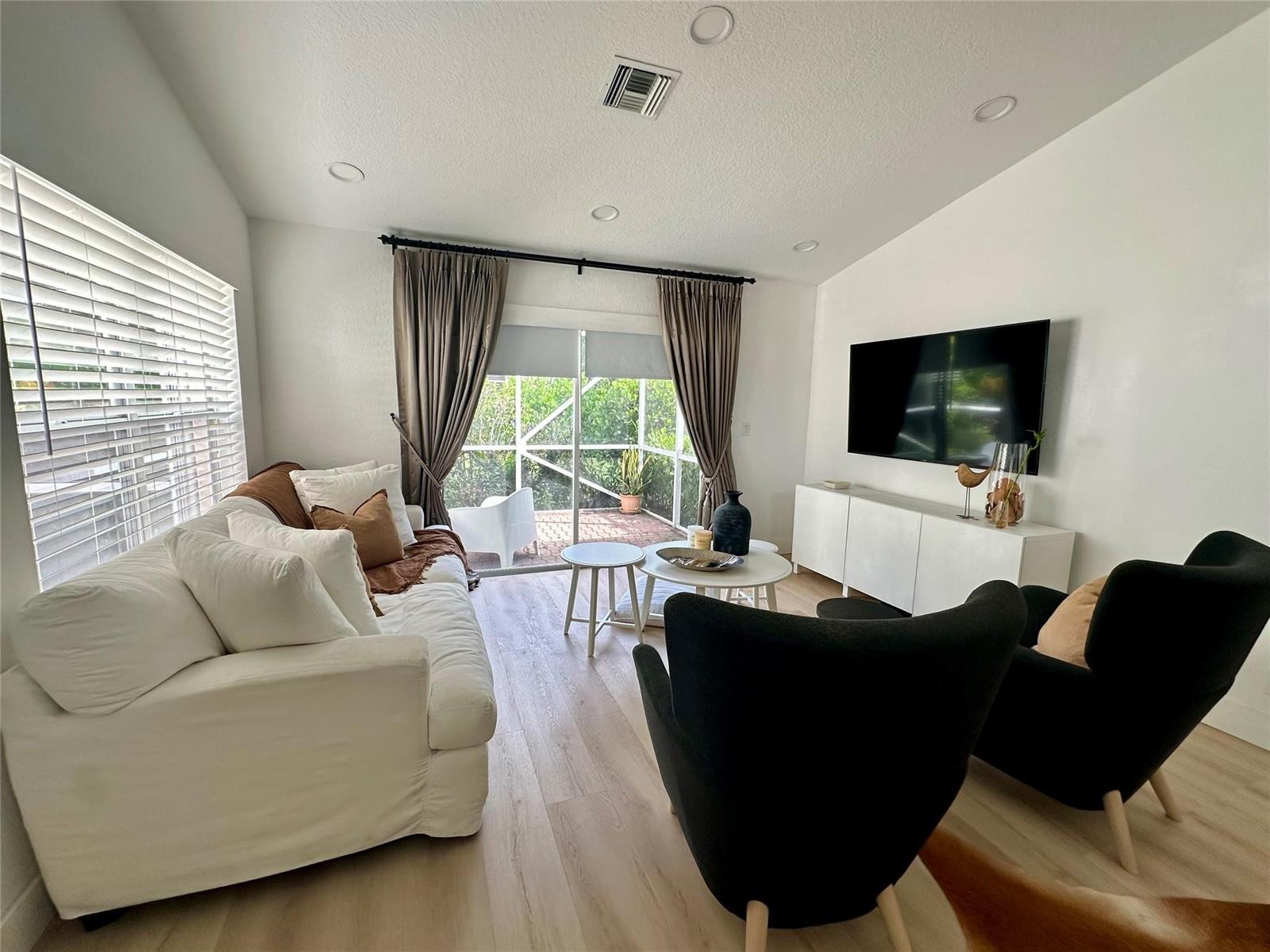A living room features a white sofa, two black armchairs, and a wall-mounted television — 7267 Panache Way, Boca Raton FL 33433, BOCA RATON, FL