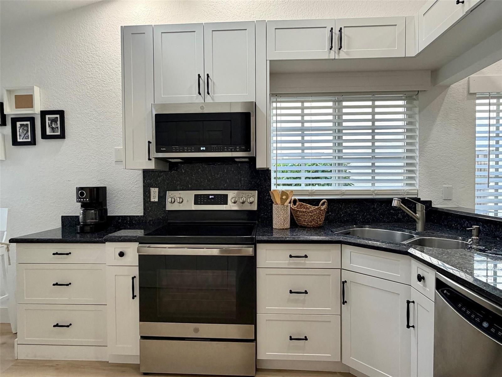 A kitchen features white cabinets, dark granite countertops, stainless steel appliances, and a window — 7267 Panache Way, Boca Raton FL 33433, BOCA RATON, FL