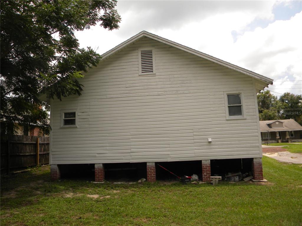The exterior of a white, elevated house with brick piers and a gable roof — 1016 NE 8TH AVENUE, OCALA, FL