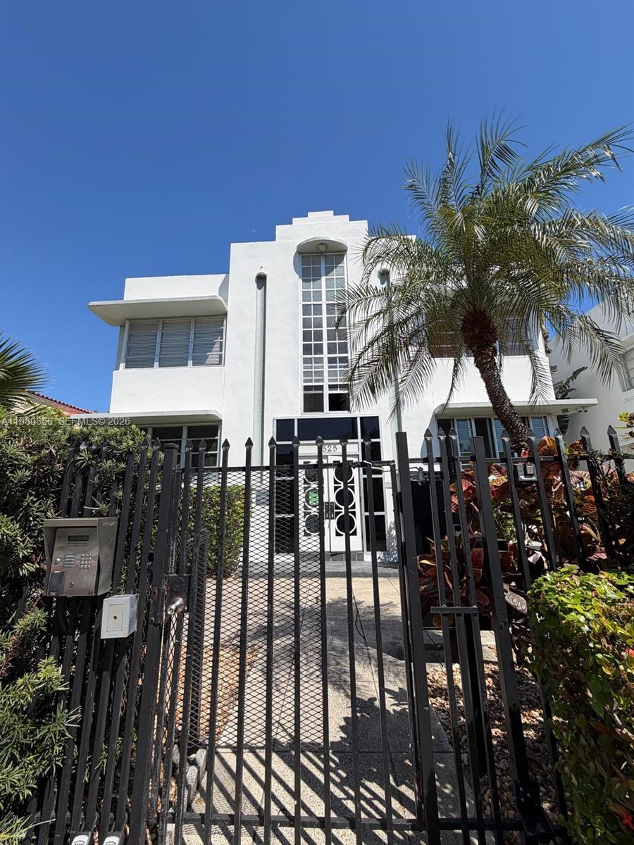 A white two-story Art Deco building stands behind a black metal fence and gate — 1525 Meridian Ave # 108, Miami Beach FL 33139, MIAMI BEACH, FL