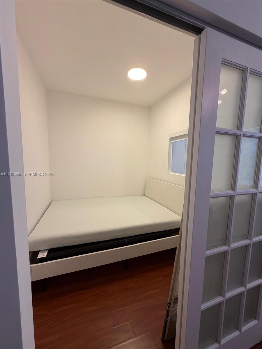 A small bedroom features a bed, white walls, and wood-look flooring — 1525 Meridian Ave # 108, Miami Beach FL 33139, MIAMI BEACH, FL
