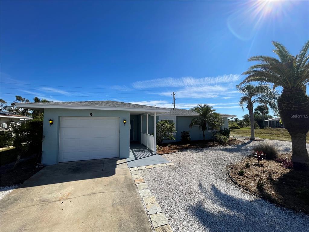 A light blue single-story house features a white garage door and a gravel driveway — 9 ANNAPOLIS LANE, ROTONDA WEST, FL