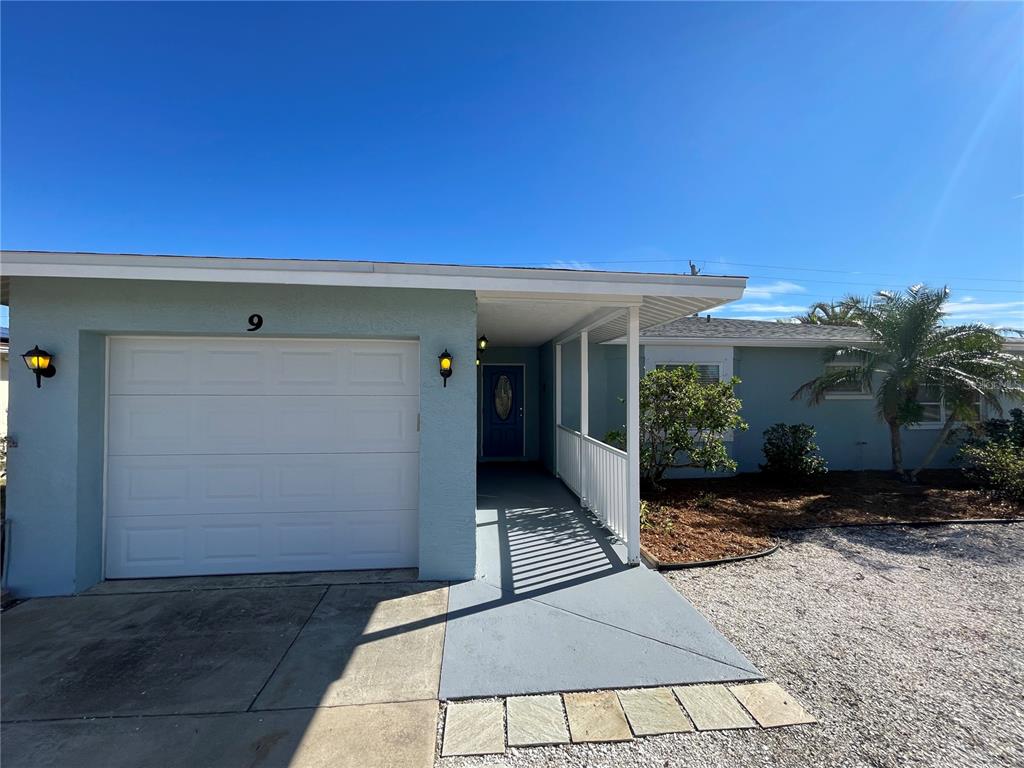 A light blue single-story house features a white garage door and a covered front entryway — 9 ANNAPOLIS LANE, ROTONDA WEST, FL