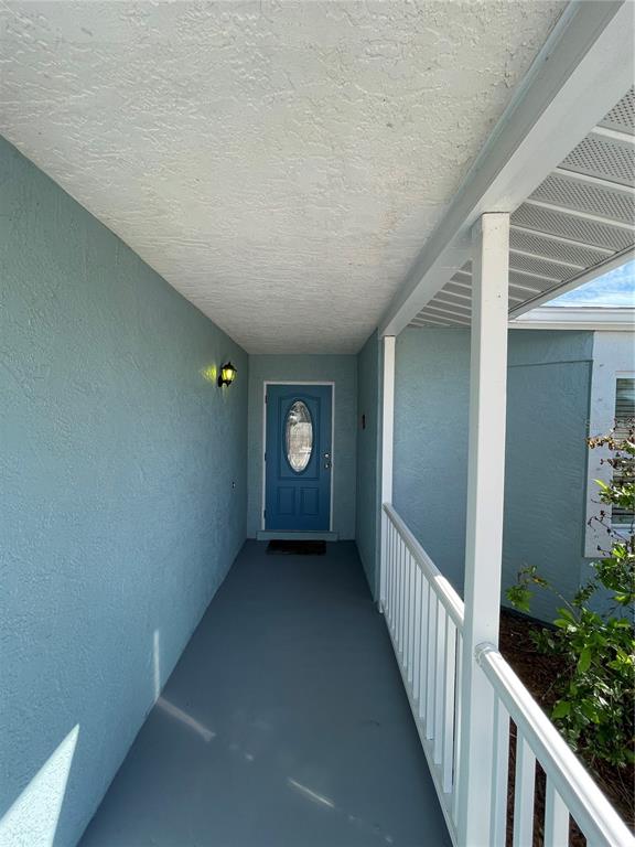 A covered porch leads to a blue front door with an oval glass insert — 9 ANNAPOLIS LANE, ROTONDA WEST, FL