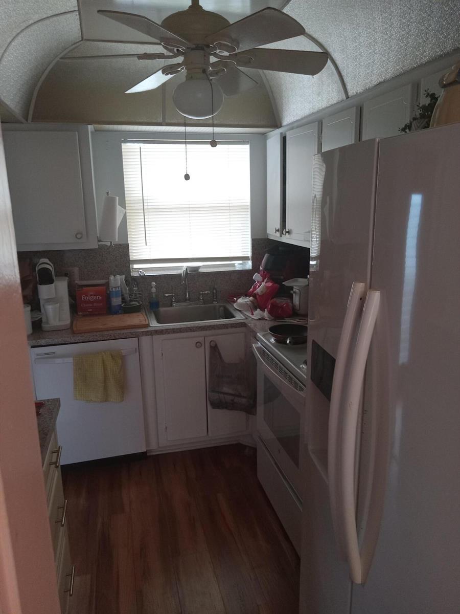 A small kitchen features white cabinets, a ceiling fan, a window, and white appliances — 2901 E Sunrise Lakes Drive E # 202, Sunrise FL 33322, SUNRISE, FL