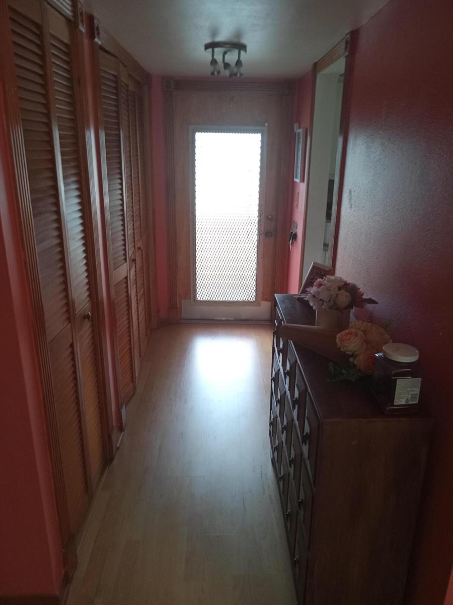 A hallway features red walls, wood-paneled closet doors, light wood flooring, and a wooden dresser — 2901 E Sunrise Lakes Drive E # 202, Sunrise FL 33322, SUNRISE, FL