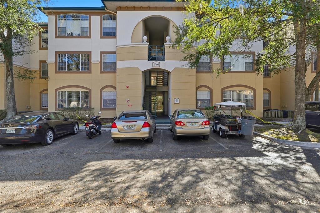 A three-story apartment building exterior features a central stairwell entrance and a paved parking lot — 17106 CARRINGTON PARK DRIVE UNIT 623, TAMPA, FL