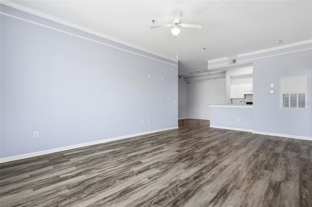An empty living room with light blue walls, wood-look flooring, and an open kitchen area — 17106 CARRINGTON PARK DRIVE UNIT 623, TAMPA, FL
