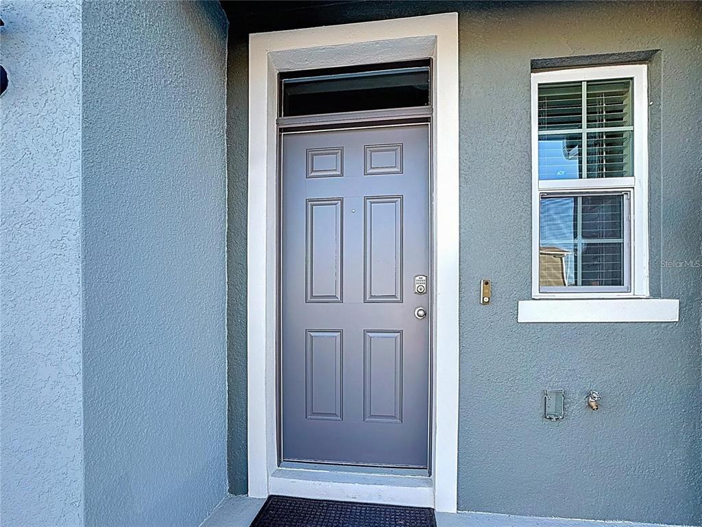 A gray front door with a keypad lock sits next to a window on a house — 3140 GOOSE ROAD, DAVENPORT, FL