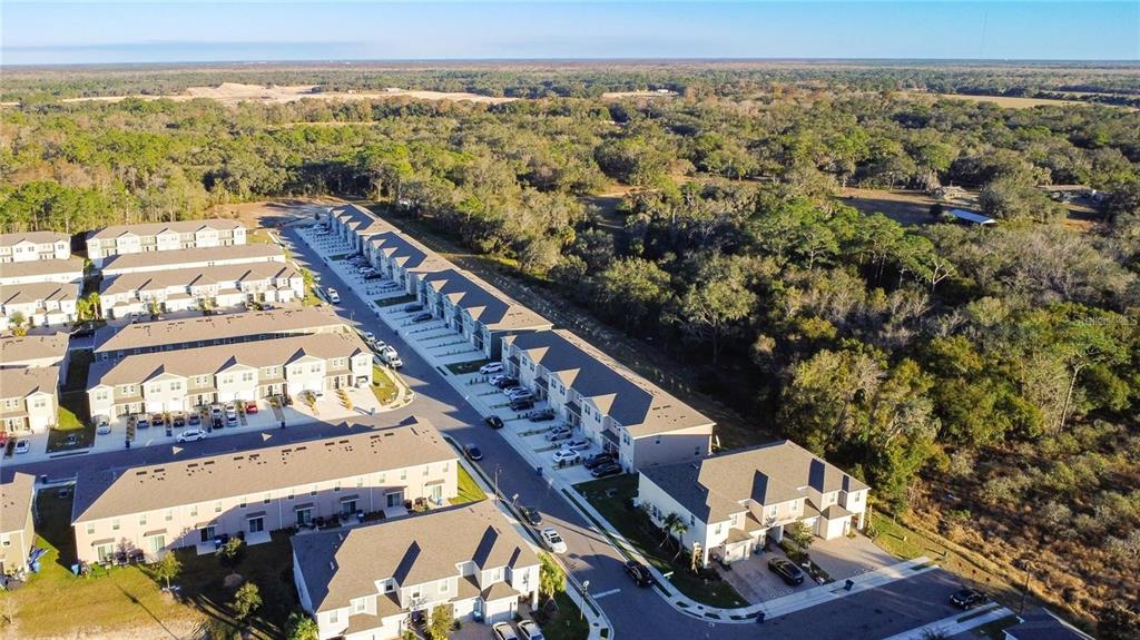 An aerial view shows several rows of multi-story townhomes surrounded by dense wooded areas — 3140 GOOSE ROAD, DAVENPORT, FL