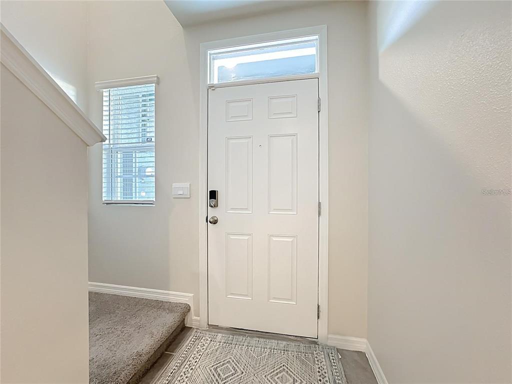 An entryway features a white front door with a transom window and carpeted stairs nearby — 3140 GOOSE ROAD, DAVENPORT, FL