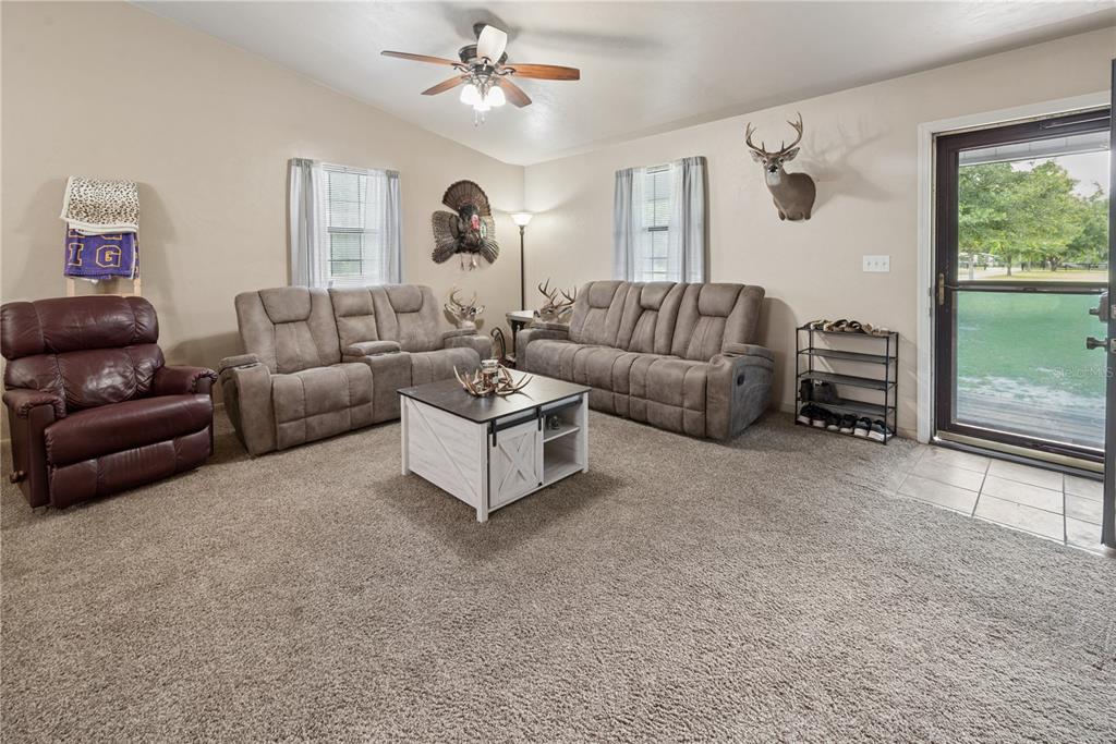 A living room features carpeted floors, a ceiling fan, two sofas, a recliner, and taxidermy — 5127 SW COUNTY ROAD 18A, LAKE BUTLER, FL