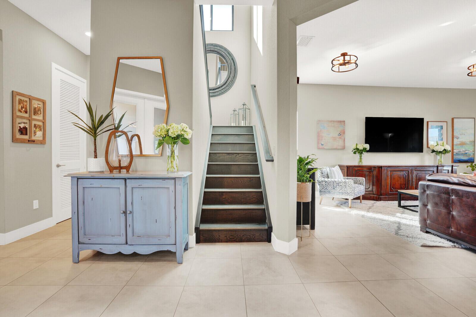 A foyer features a blue cabinet, a staircase, and an open view into a living room — 10767 Pacifica Way, Parkland FL 33076, PARKLAND, FL