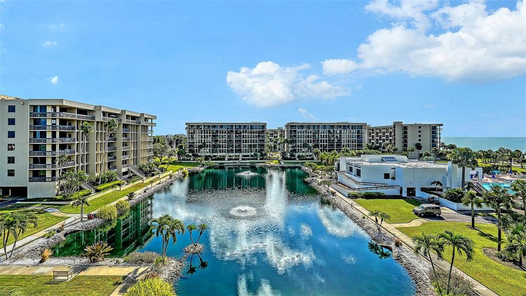 An aerial view of a pond surrounded by multi-story apartment buildings and palm trees — 1115 GULF OF MEXICO DRIVE UNIT 401, LONGBOAT KEY, FL
