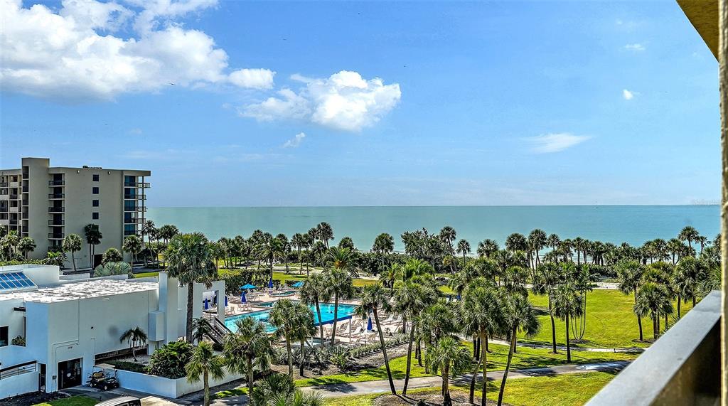 An elevated view shows a swimming pool, palm trees, and the ocean from a balcony — 1115 GULF OF MEXICO DRIVE UNIT 401, LONGBOAT KEY, FL