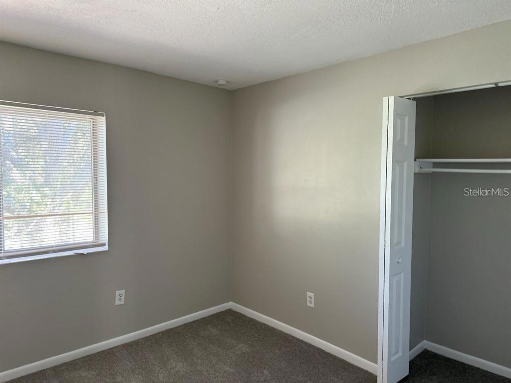 A bedroom with gray walls, carpeted flooring, a window with blinds, and an open closet — 5855 16TH STREET S UNIT 6, ST PETERSBURG, FL