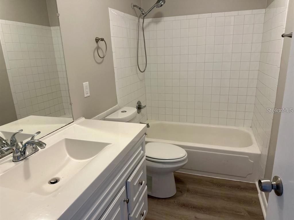 A bathroom features a white vanity, a toilet, and a bathtub with white subway tile — 5855 16TH STREET S UNIT 6, ST PETERSBURG, FL