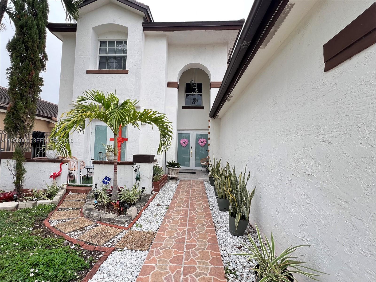 A two-story white stucco house features a tiled walkway leading to a double-door entrance — 13249 NW 9th Ln, Miami FL 33182, MIAMI, FL