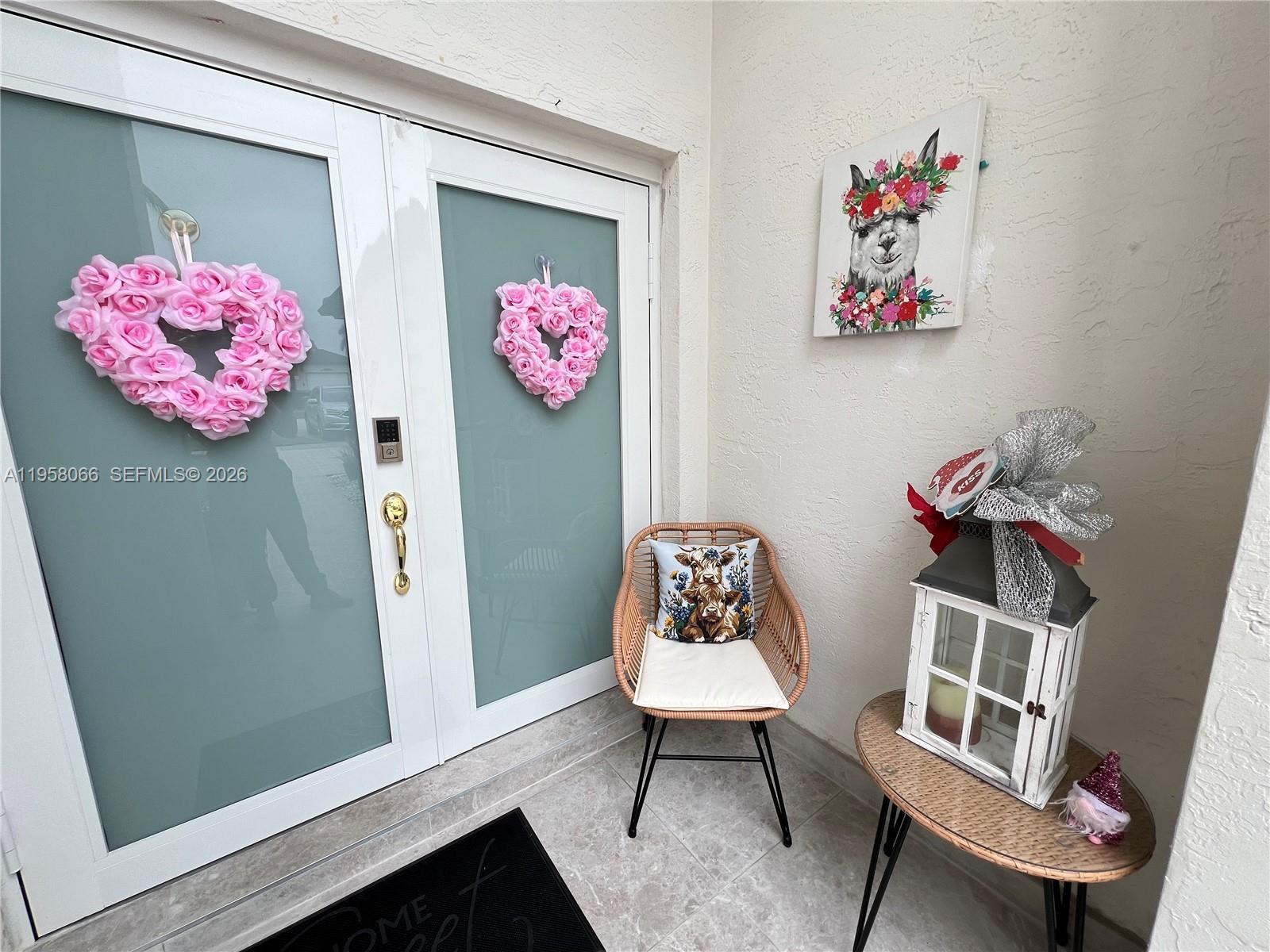 A patio features double glass doors with heart wreaths, a wicker chair, and a lantern — 13249 NW 9th Ln, Miami FL 33182, MIAMI, FL