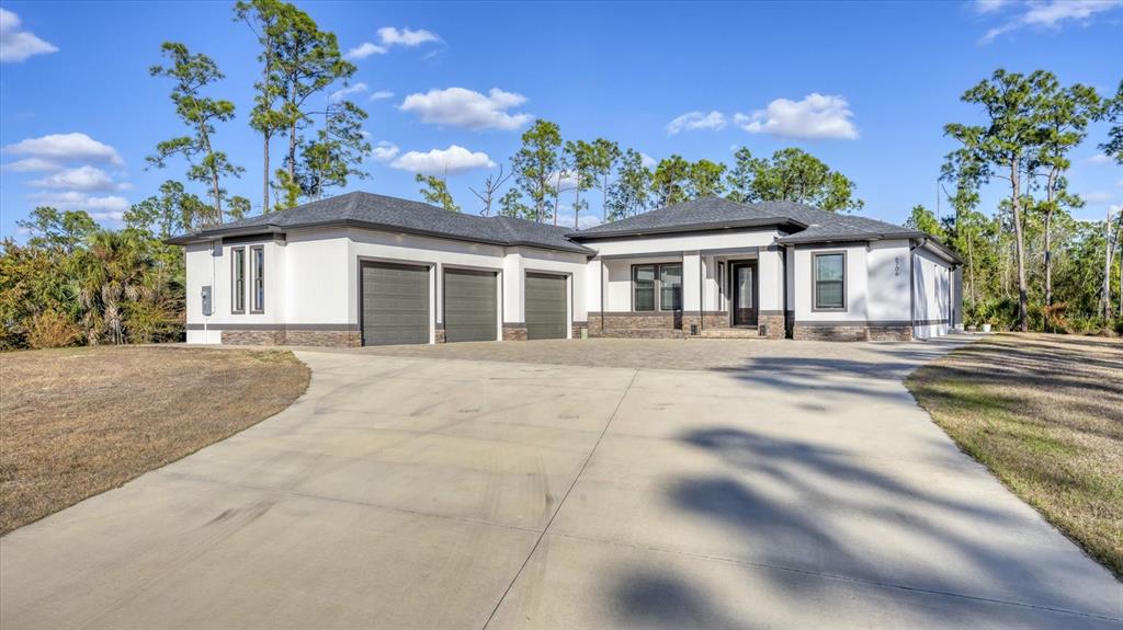 A single-story house with a three-car garage, white stucco walls, and a paved driveway — 6706 TANEYTOWN STREET, NORTH PORT, FL