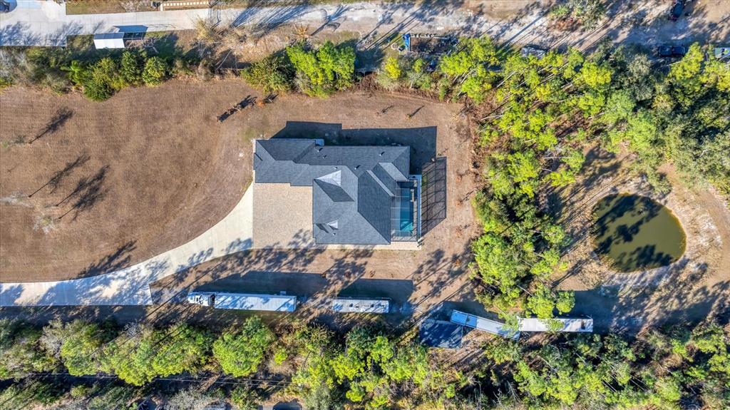 An aerial view shows a house with a pool, driveway, and trailers on a wooded lot — 6706 TANEYTOWN STREET, NORTH PORT, FL