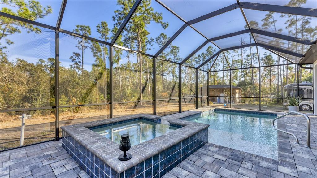 A screened-in patio features a tiled hot tub and swimming pool with paver decking — 6706 TANEYTOWN STREET, NORTH PORT, FL