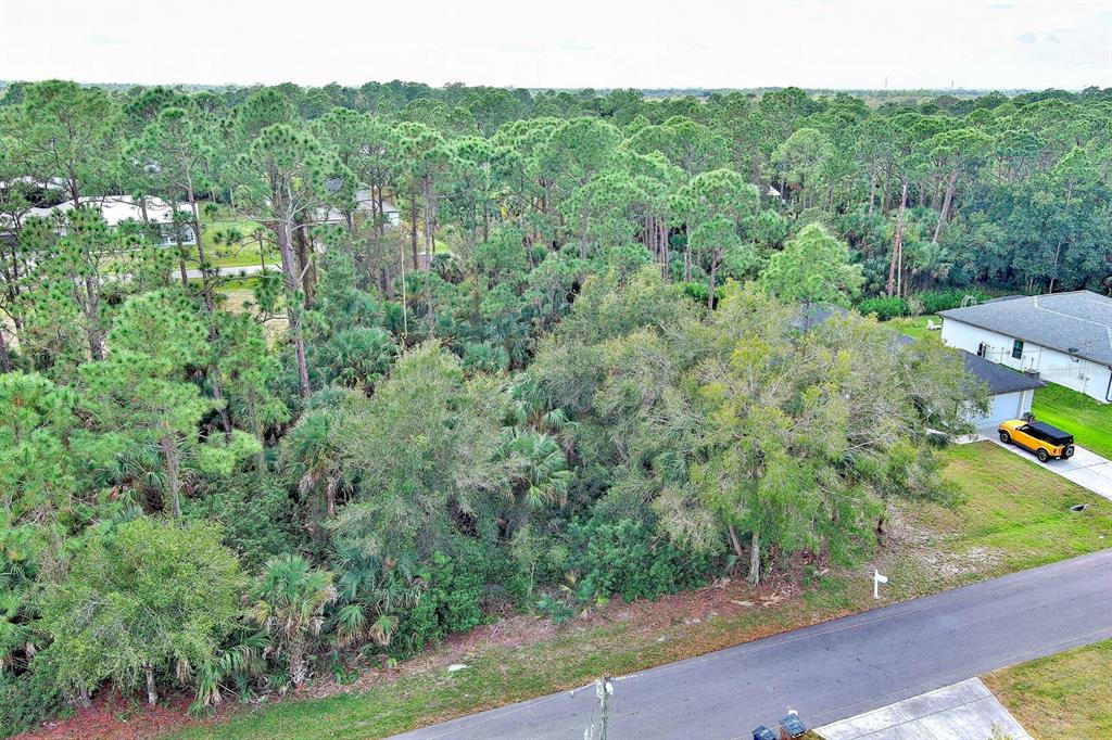 An aerial view shows a vacant, wooded residential lot situated between two houses — 3847 HIGHLIGHT STREET, FORT MYERS, FL