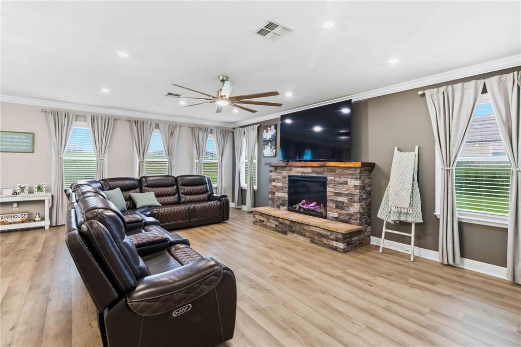 A living room features a stone fireplace, a large sectional sofa, and light wood flooring — 10007 DOLPHIN GULL CIRCLE, THONOTOSASSA, FL