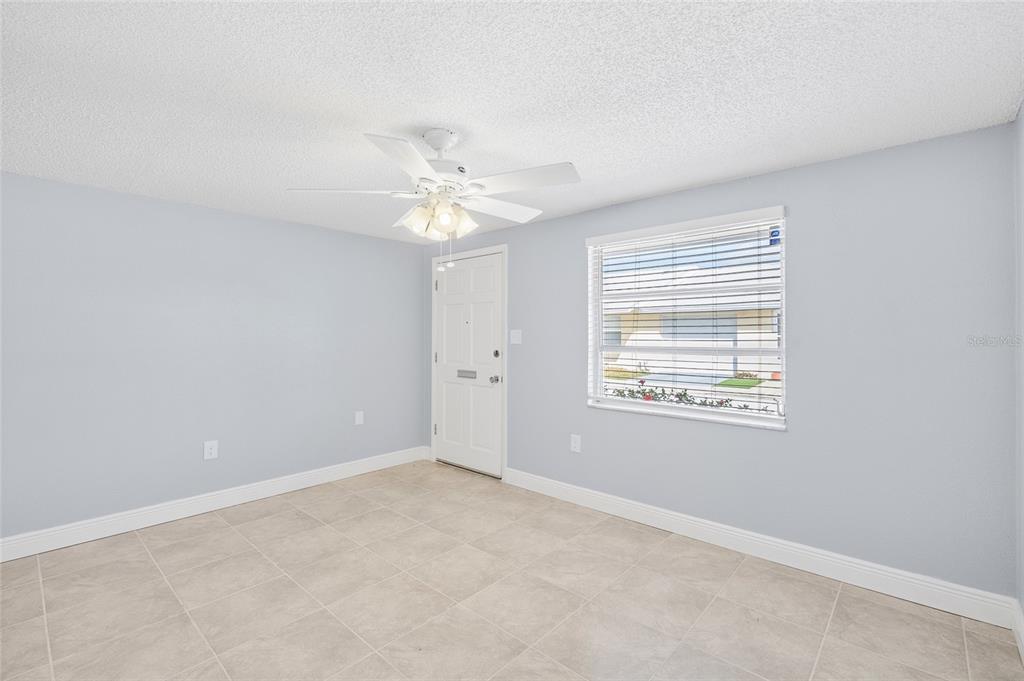 An empty room with light blue walls, tile flooring, a ceiling fan, and a white door — 4948 GETNER STREET, NEW PORT RICHEY, FL