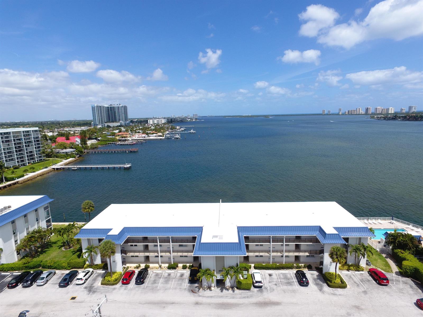 An aerial view of a multi-story apartment building with a parking lot and waterfront — 400 Wilma Circle # 207, Riviera Beach FL 33404, RIVIERA BEACH, FL