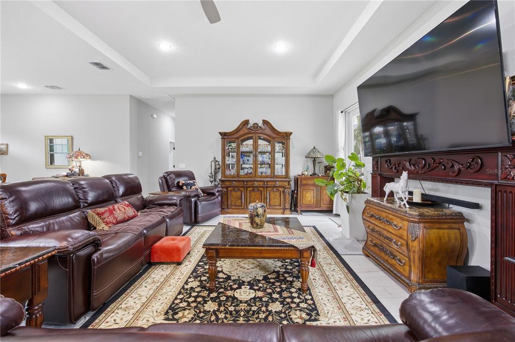 A living room features leather sofas, a dark wood hutch, and a large television — 5070 SW 129TH COURT, OCALA, FL