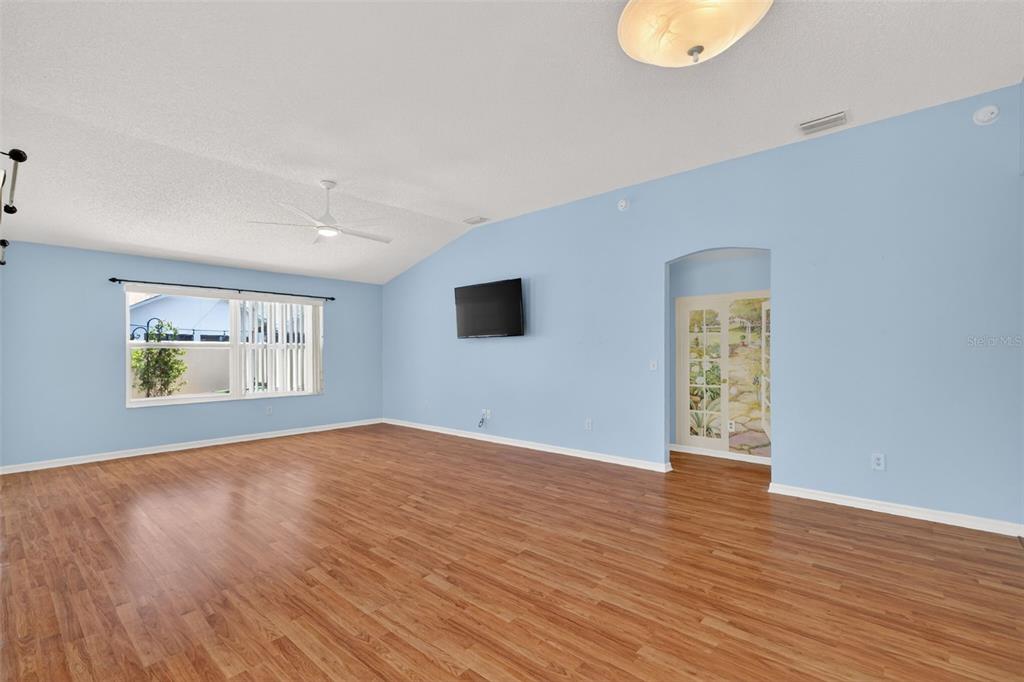 A spacious living room features light blue walls, wood-look flooring, and a ceiling fan — 17755 SE 84TH SHELDON TERRACE, THE VILLAGES, FL