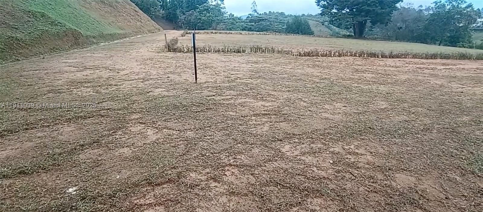 A wide, flat, grassy lot with a dirt surface and a single post in the center — Vereda Mampuesto Sector Garrido #14, C Colombia, C