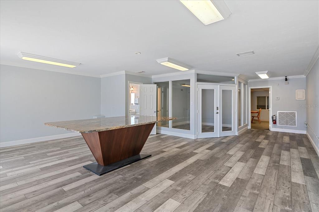 A room with gray wood-look flooring, a large granite island, and glass-paneled office doors — 236 GROVE STREET S, VENICE, FL