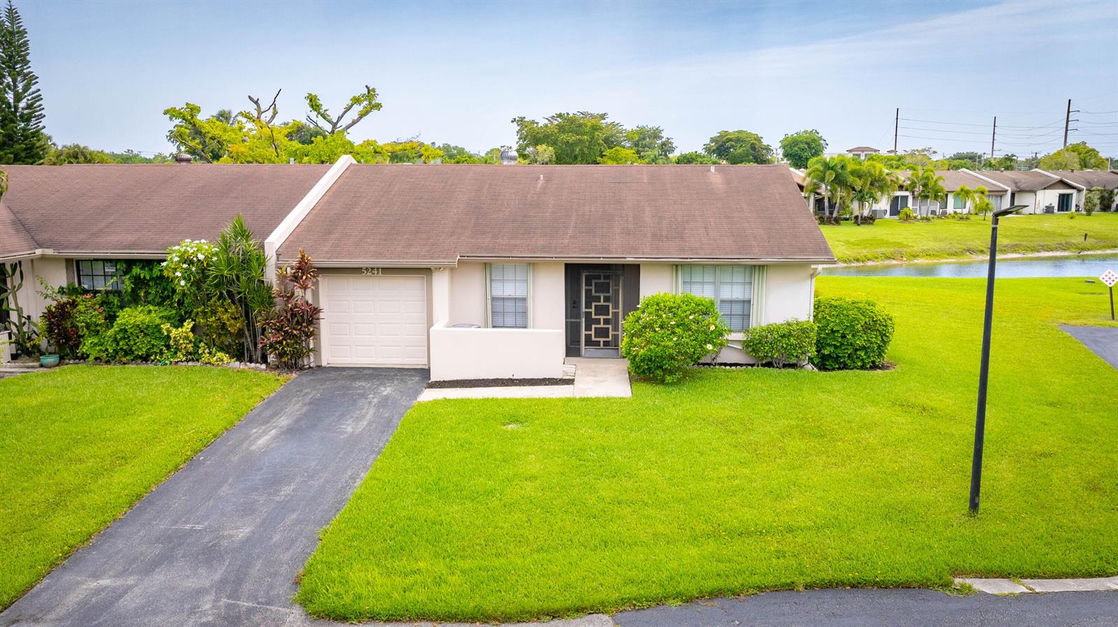 A single-story townhouse with a brown shingled roof, a garage, and a front lawn — 5241 Breadfruit Circle, Delray Beach FL 33484, DELRAY BEACH, FL