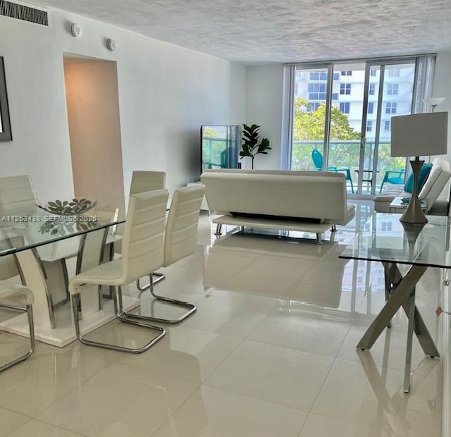 A bright living and dining area features white tile floors, modern furniture, and a balcony view — 3801 S Ocean Dr # 3C, Hollywood FL 33019, HOLLYWOOD, FL