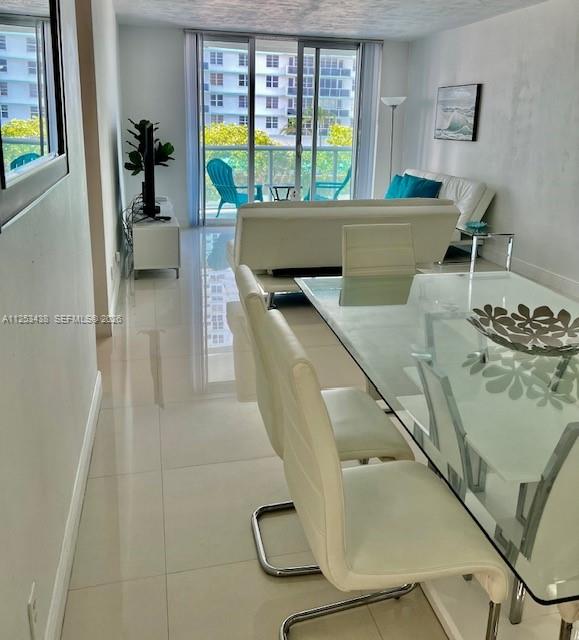 A bright dining and living area features white tile floors, a glass table, and balcony views — 3801 S Ocean Dr # 3C, Hollywood FL 33019, HOLLYWOOD, FL