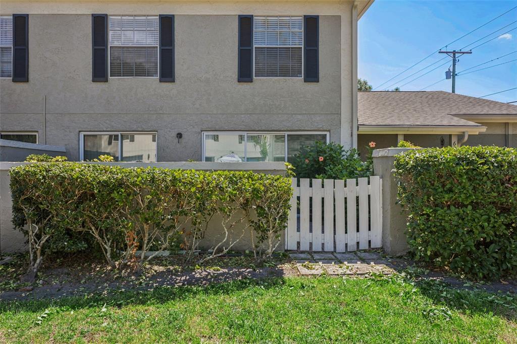 A two-story townhouse exterior features a white picket gate, hedge landscaping, and dark shutters — 6341 TREETOP CIRCLE UNIT 6341, TEMPLE TERRACE, FL