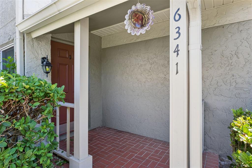 A covered entryway features a red brick floor, a red door, and a house number — 6341 TREETOP CIRCLE UNIT 6341, TEMPLE TERRACE, FL
