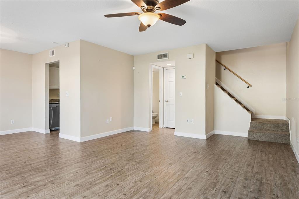 An open living area features wood-look flooring, a ceiling fan, and stairs leading upward — 6341 TREETOP CIRCLE UNIT 6341, TEMPLE TERRACE, FL